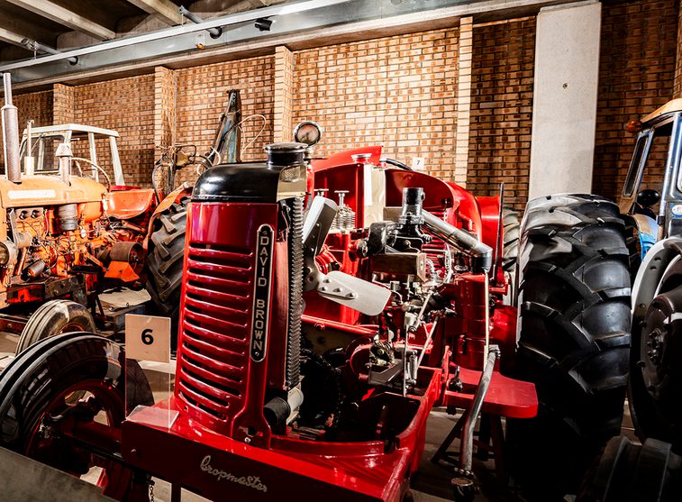 A red compact tractor with 2 large black rubber wheels at the rear and 2 smaller black ridged rubber wheels at the front