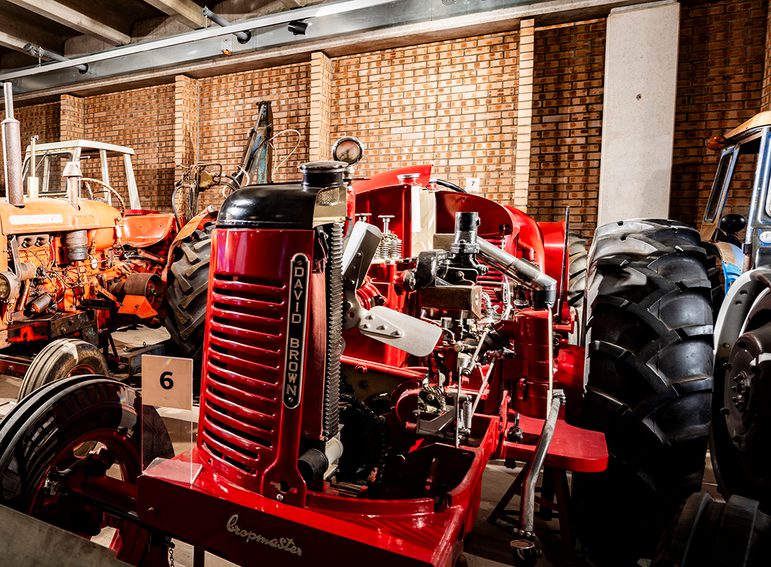A red compact tractor with 2 large black rubber wheels at the rear and 2 smaller black ridged rubber wheels at the front