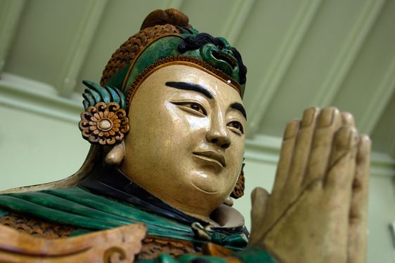 Close up of the head and praying hands of a Buddhist Weituo sculpture.