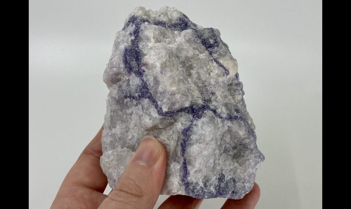 A white mineral with purple veins.
