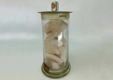 A glass jar with blocks of pale pink nitre.
