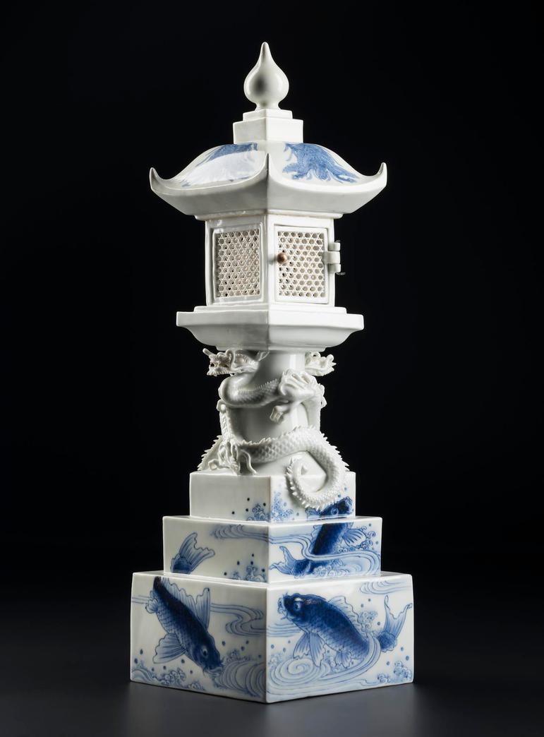A white porcelain lantern sitting a block pedestal decorated with blue carp.