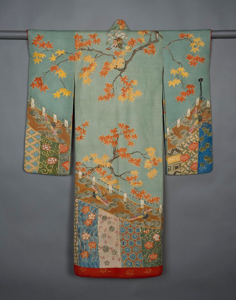 A light blue robe hanging on a rod with long wide sleeves featuring a floral tree pattern.