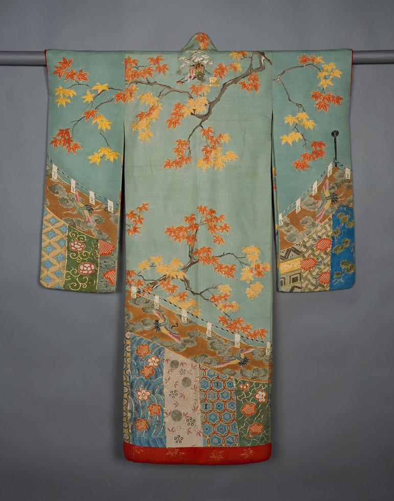 A light blue robe hanging on a rod with long wide sleeves featuring a floral tree pattern.