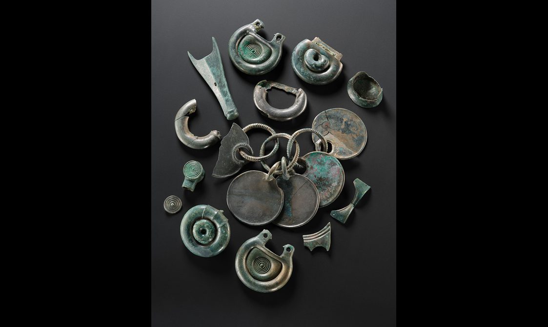 An assortment of intricately designed objects and fragments of objects making up a Bronze Age hoard.