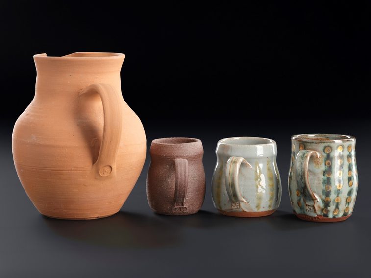 A large jug and three smaller glazed mugs with different line and dot patterns.