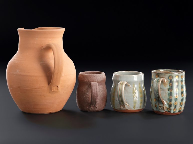 A large jug and three smaller glazed mugs with different line and dot patterns.