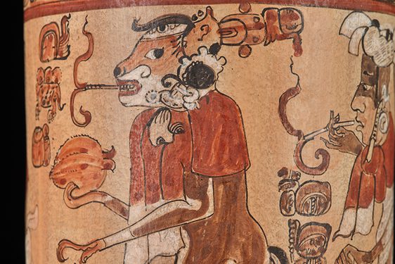 Ancient Mayan vase depicting a detailed illustration of a smoking monkey and human figures, adorned with intricate glyphs and traditional motifs.