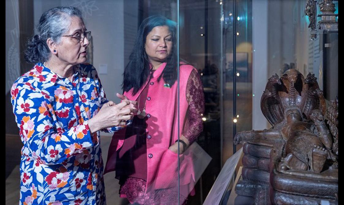 Two people look at a sculpture sat within a glass case