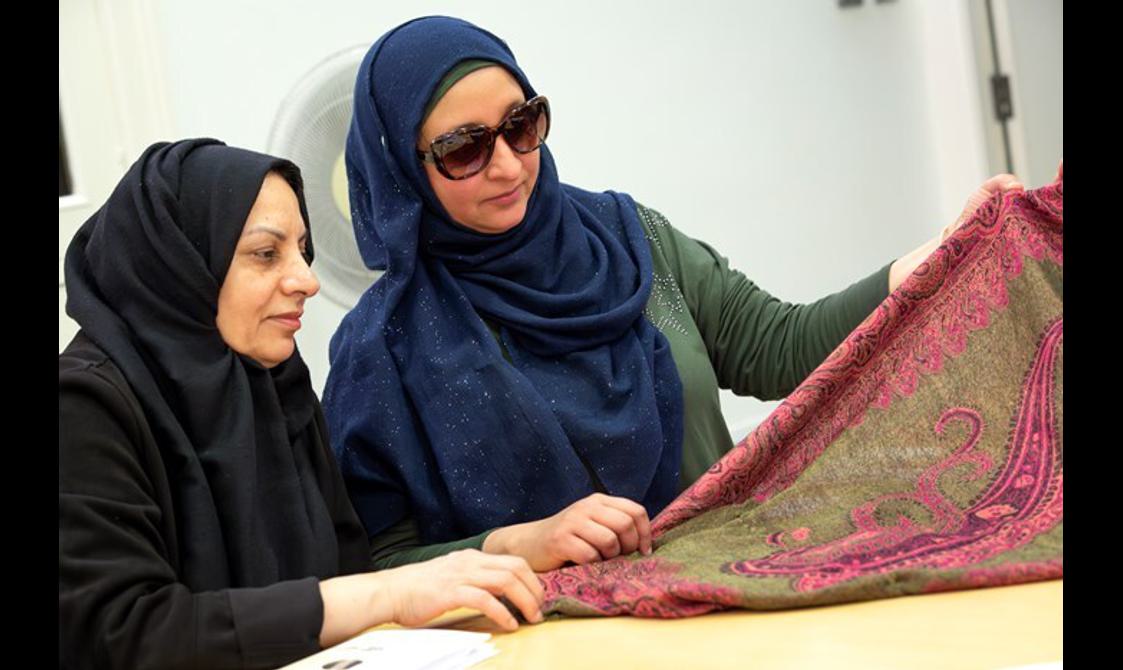 Two people look at a pink and green toned piece of cloth
