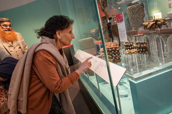 A person points in admiration at an anklet in a display case