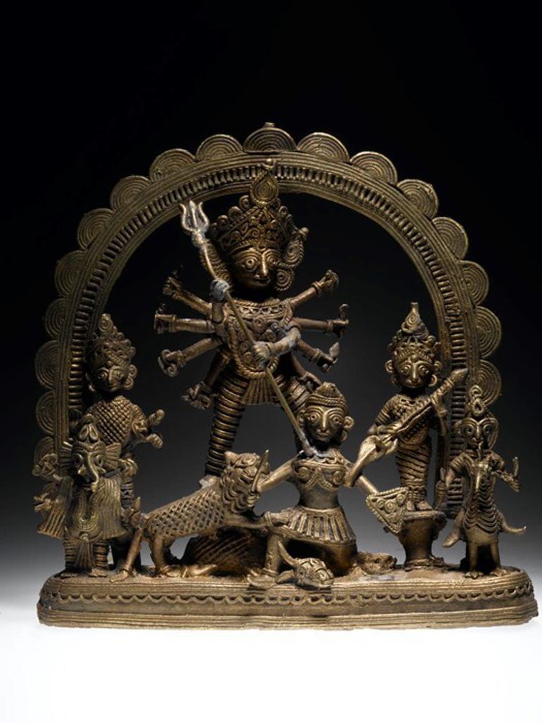 An intricate brass object depicting a figure defeating a buffalo-like creature