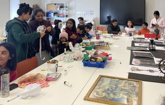 A group of people engage in mask making activities around a table