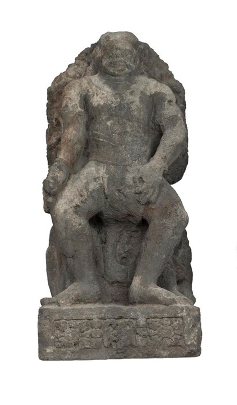 A damaged grey stone sculpture of a monkey-like figure