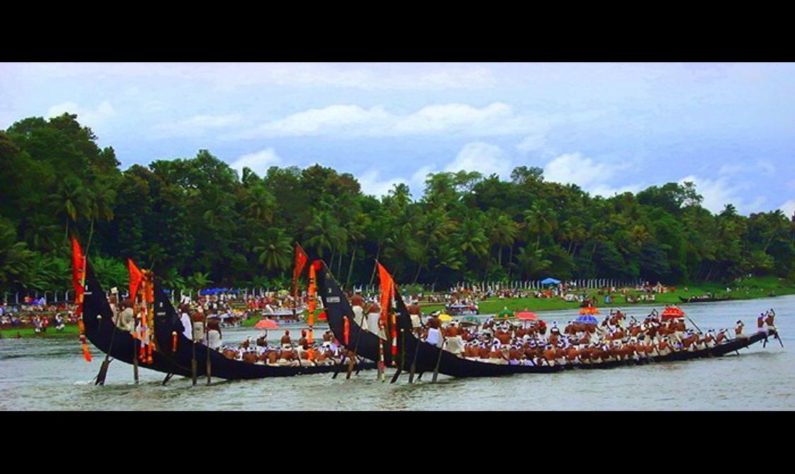 Boats adorned with red flags are sailing down a river