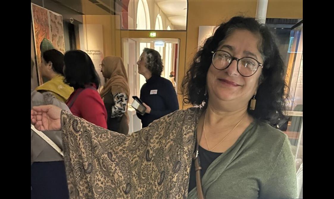 A person adorned with a Paisley scarf smiles happily