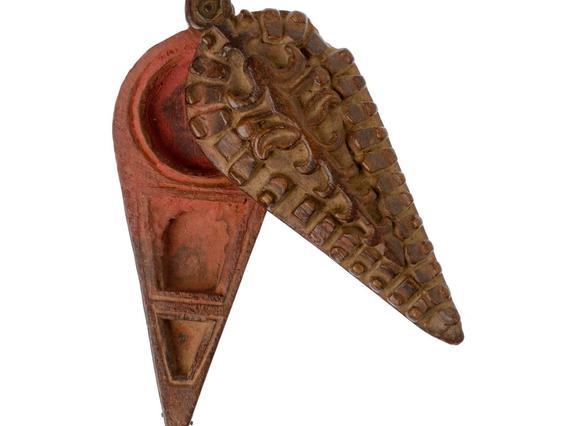 A small pot with a triangular handle, with a reddish coloured interior