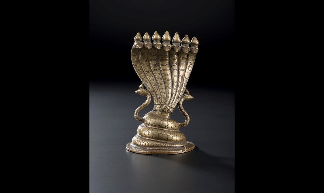 A golden metal figure depicting a snake with seven heads