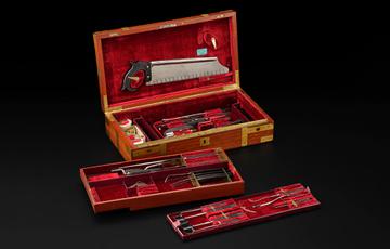 A surgical kit in a wooden box lined with red velvet.