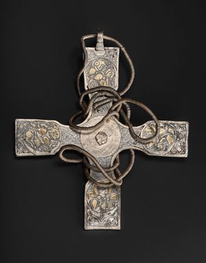 A metal pectoral cross with intricate carved designs on the arms.