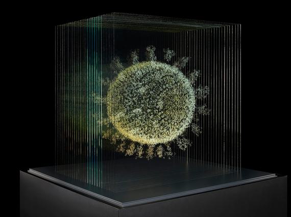 An artistic light installation of a virus cell, lit with yellow and blue colours, in a museum display case. It's been placed in front of a black backdrop.