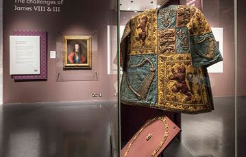 Garments on display in the Bonnie Prince Charlie and the Jacobites exhibition, with focus on a top with quadrant designs of the royal coat of arms.