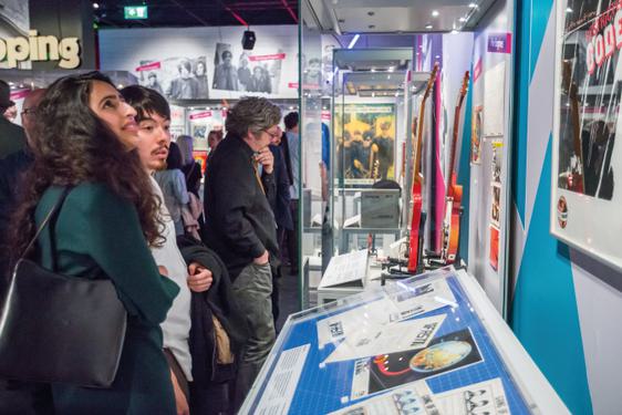 Visitors look at items in a case in a crowded gallery