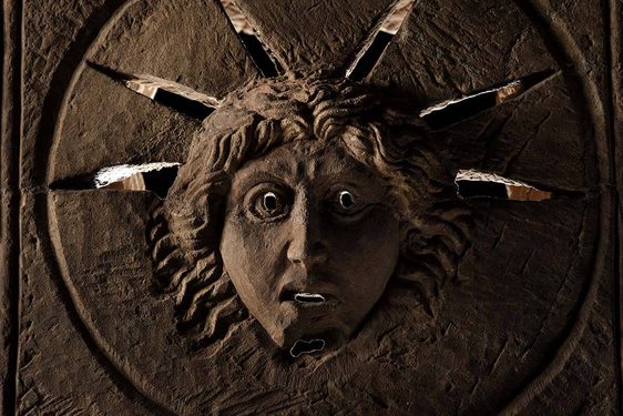 A Roman stone altar with the face of the Roman god Sol carved into it. Rays of light pass through slits around the head of Sol.