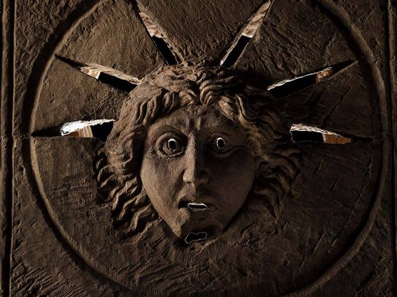 A Roman stone altar with the face of the Roman god Sol carved into it. Rays of light pass through slits around the head of Sol.