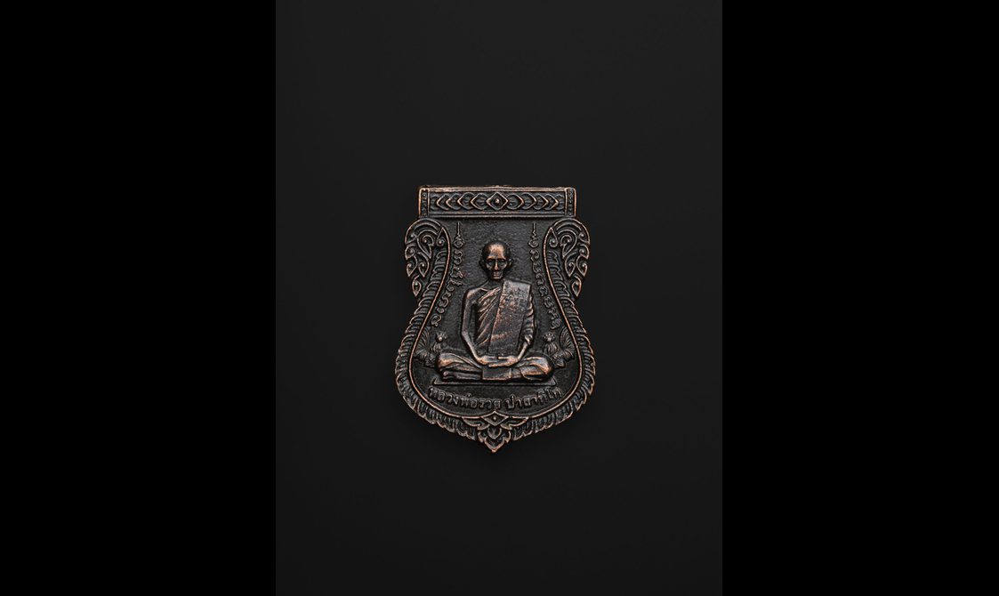 A small amulet in the shape of a shield with a Buddha figure carved on it.