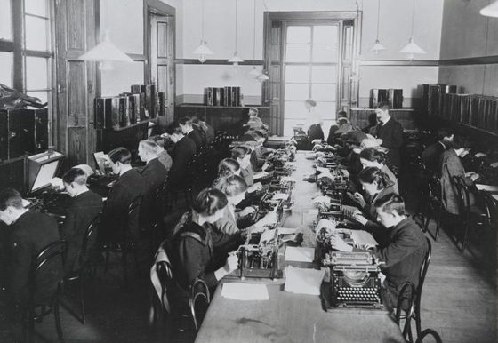 A black and white photograph of four rows of people using typewriters.
