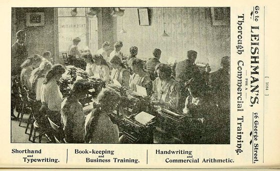 A black and white photograph of two rows of people using typewriters.