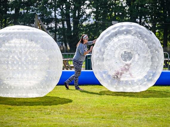 Woman pushing zorbing ball with child inside