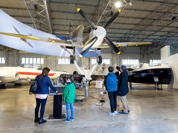 A family are in the aviation hanger at the National Museum of Flight, and standing beneath a spitfire suspended from the ceiling