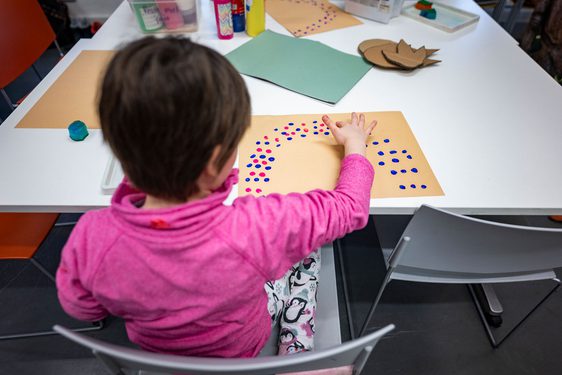 A child doing some finger painting while sitting at a table