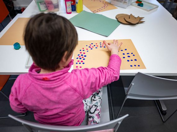 A child doing some finger painting while sitting at a table