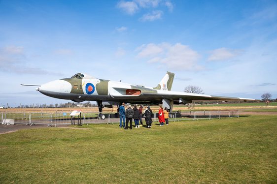 A group of visitors standing in an airfield next to a Vulcan aircraft