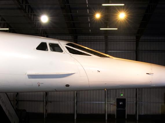 The front section of concorde, showing the pilot's cabin and nose of the plane. The concorde is inside a hangar in a museum
