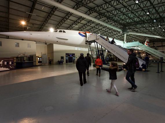 People walking around the Concorde in a large aircraft hangar.