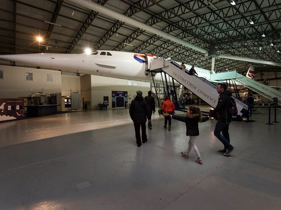 People walking around the Concorde in a large aircraft hangar.