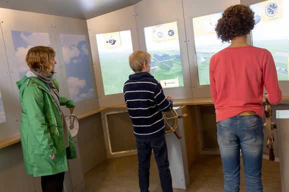 Visitors playing a flight simulator game in the Fantastic Flight gallery.