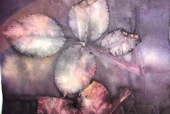 A close-up of leaves on a stem printed in hues of purple, pink and grey on fabric.