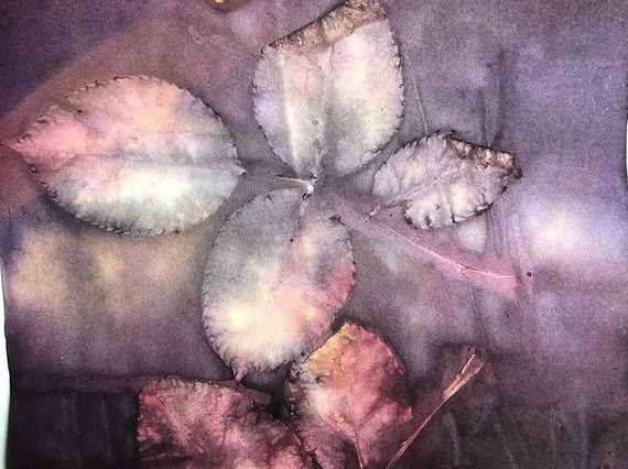 A close-up of leaves on a stem printed in hues of purple, pink and grey on fabric.