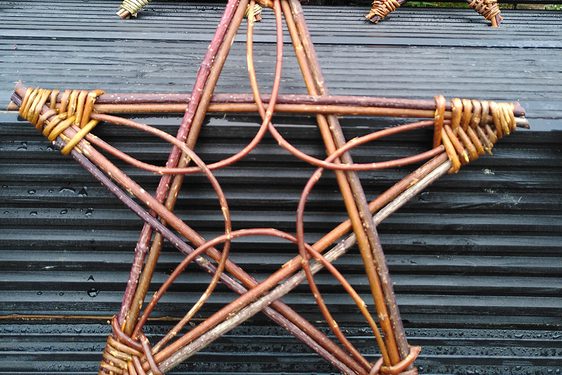 A star decoration made of willow branches, with a grey tile background.