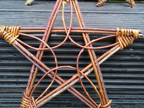 A star decoration made of willow branches, with a grey tile background.