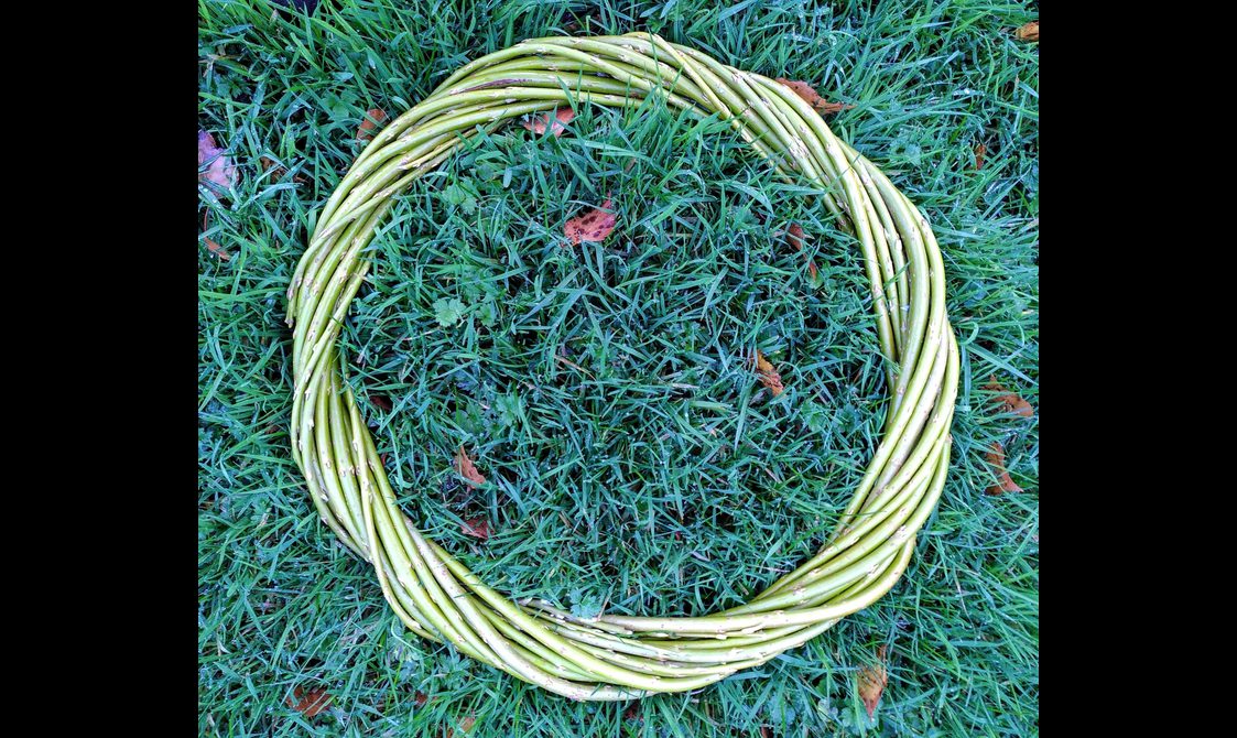 A willow wreath decoration made out of willow against grass.