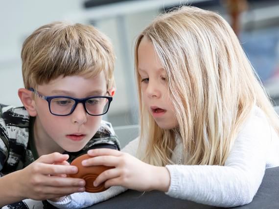 Two children look closely at an artefact