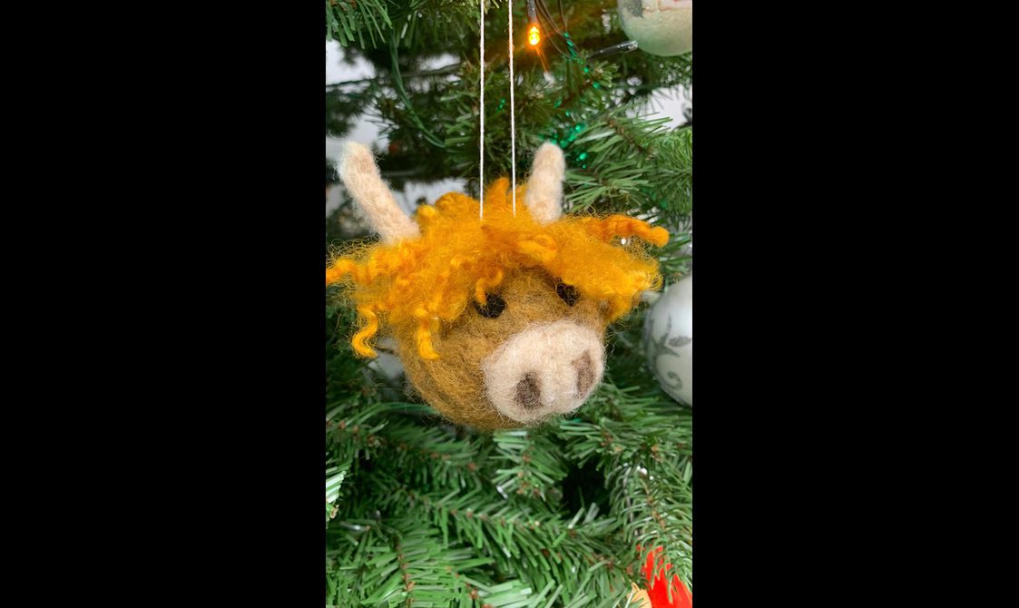 Highland cow-shaped decoration hanging from a tree