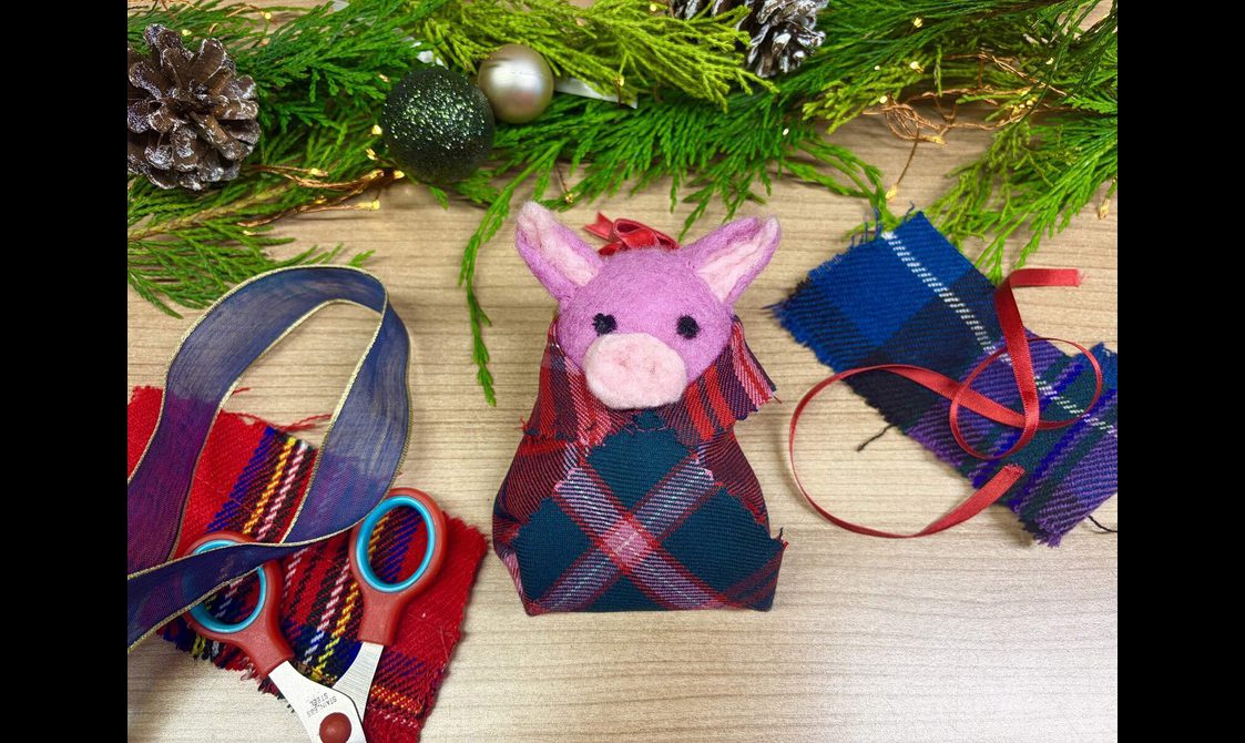 A felt pig decoration and surrounded by fabric and craft scissors