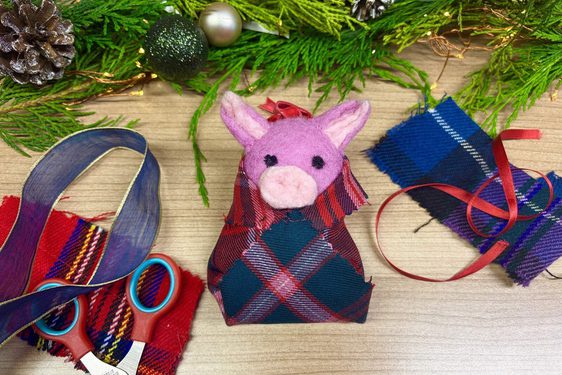 A felt pig decoration and surrounded by fabric and craft scissors